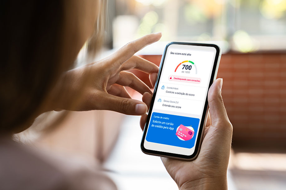 Foto mostra mulher consultando score em um celular, que mostra pontuação 700