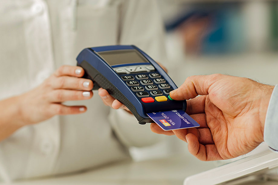 Foto mostra pessoa passando cartão de crédito na máquina